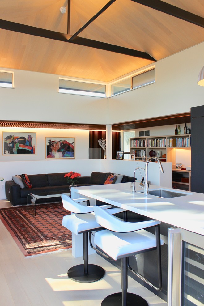 Modern inredning av ett litet loftrum, med vita väggar, ljust trägolv, en dold TV och beiget golv