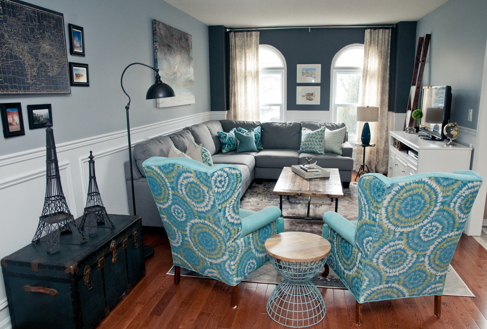 This is an example of a classic grey and teal open plan living room in Toronto with grey walls, medium hardwood flooring and a freestanding tv.