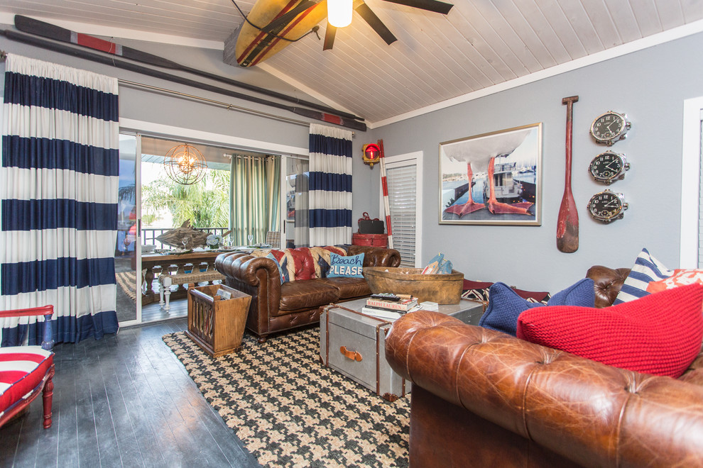 Design ideas for a large nautical open plan living room in Tampa with a home bar, multi-coloured walls, painted wood flooring, a corner fireplace, a wooden fireplace surround, a wall mounted tv and black floors.