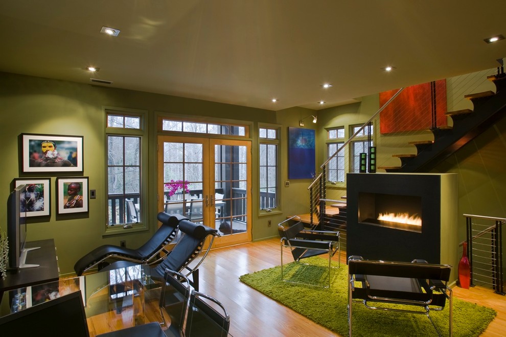 На фото: гостиная комната в современном стиле с зелеными стенами, паркетным полом среднего тона и горизонтальным камином с