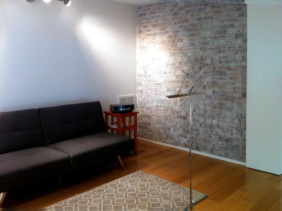 Foto de salón abierto moderno de tamaño medio con paredes blancas, marco de chimenea de ladrillo, suelo de madera en tonos medios, chimenea de doble cara y pared multimedia