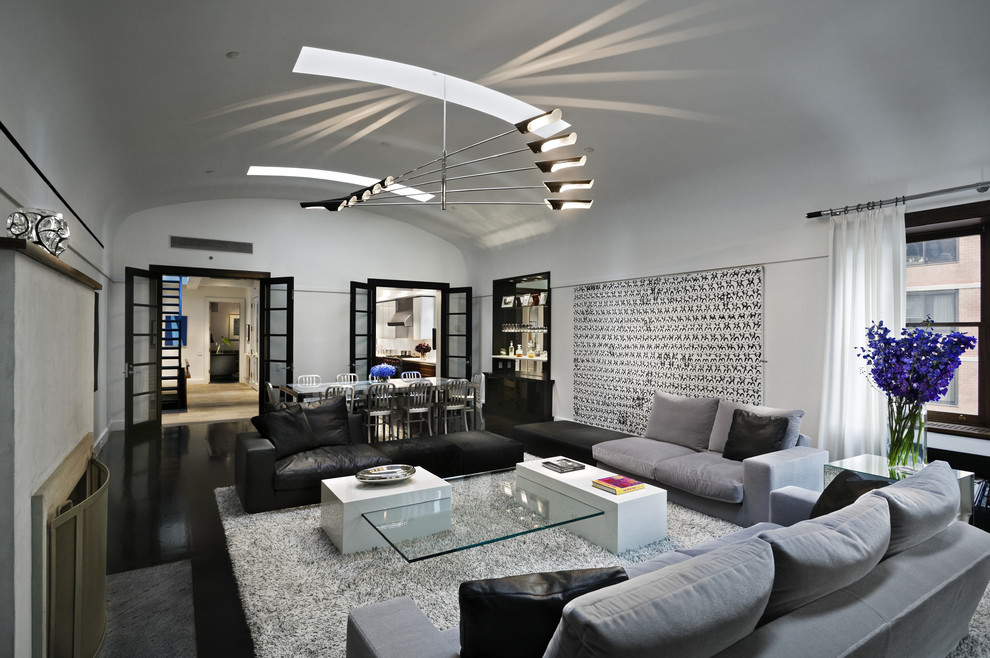 Aménagement d'un salon contemporain ouvert avec un mur blanc, une cheminée standard et canapé noir.
