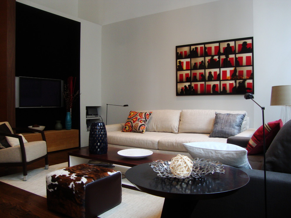 Diseño de salón tipo loft actual de tamaño medio con paredes grises, suelo de madera en tonos medios y televisor colgado en la pared
