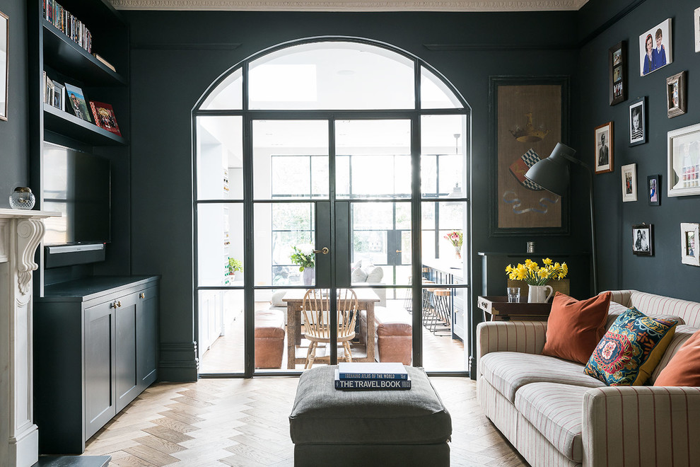Foto di un soggiorno tradizionale con pareti nere, pavimento in legno massello medio e TV a parete