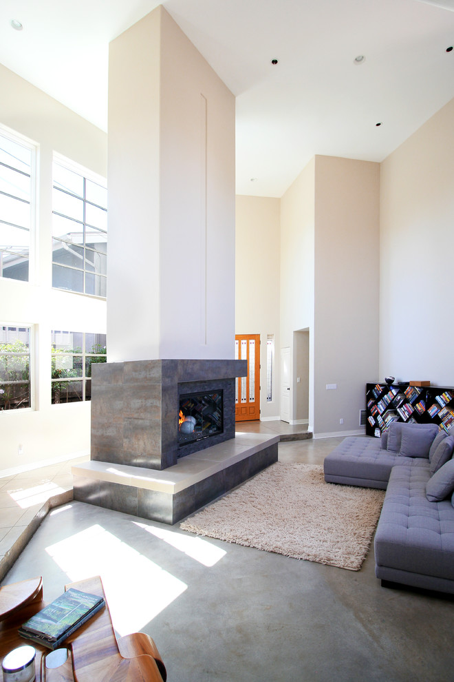 Réalisation d'un grand salon design ouvert avec un mur beige, sol en béton ciré, une cheminée standard et un manteau de cheminée en carrelage.