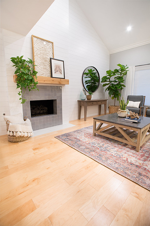 Photo of a medium sized farmhouse formal enclosed living room in Los Angeles with grey walls, light hardwood flooring, a standard fireplace, a tiled fireplace surround, no tv and brown floors.