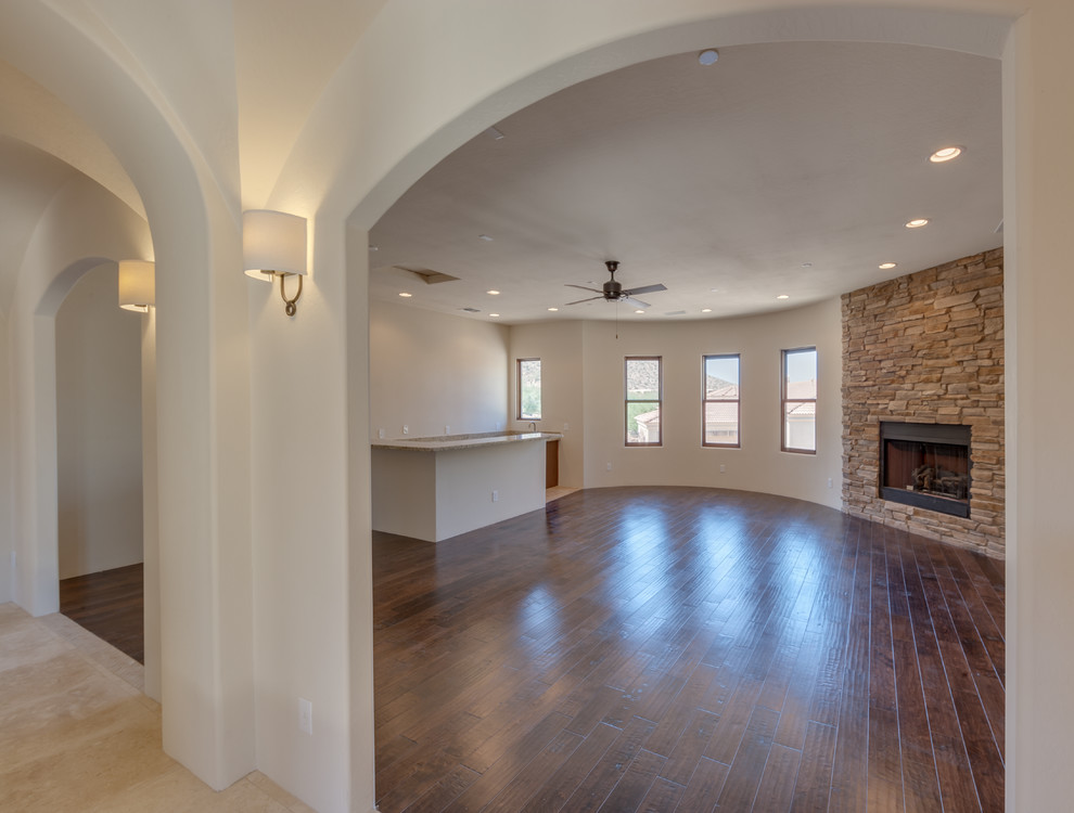 Mittelgroßes, Fernseherloses Mediterranes Wohnzimmer im Loft-Stil mit Hausbar, beiger Wandfarbe, dunklem Holzboden, Kamin und Kaminumrandung aus Stein in Phoenix