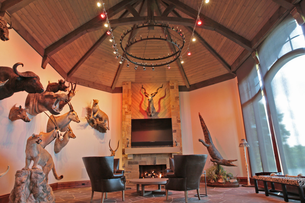 Идея дизайна: гостиная комната в стиле рустика с фасадом камина из камня, телевизором на стене, разноцветным полом и деревянным потолком