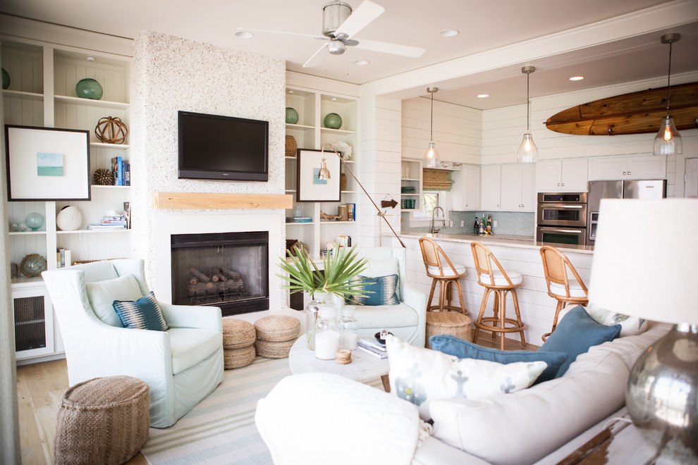 Esempio di un soggiorno tropicale aperto con pareti bianche, camino classico e TV a parete