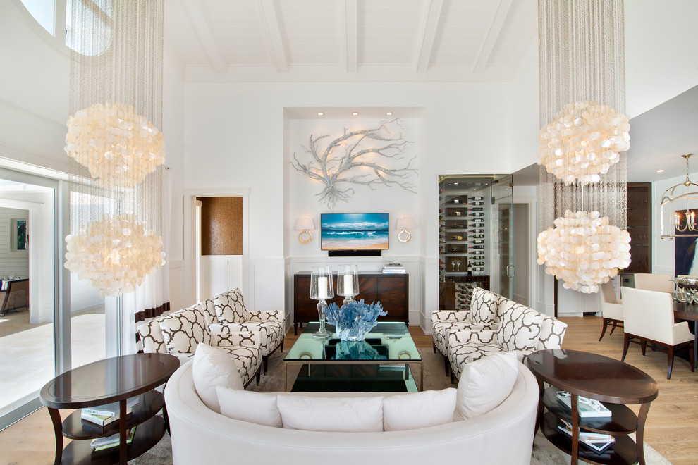 Imagen de salón abierto tropical con paredes blancas, suelo de madera en tonos medios y televisor colgado en la pared