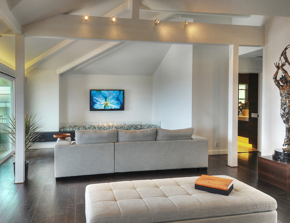 На фото: открытая гостиная комната в современном стиле с белыми стенами, полом из бамбука, фасадом камина из камня и телевизором на стене с