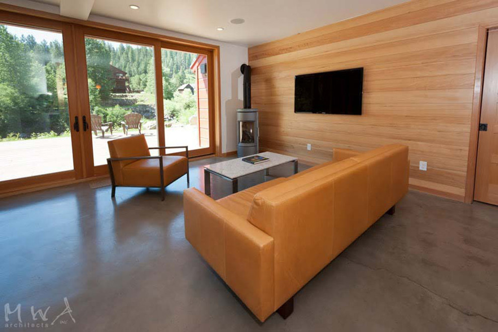 Modelo de salón abierto retro pequeño con paredes blancas, suelo de cemento, estufa de leña y televisor colgado en la pared