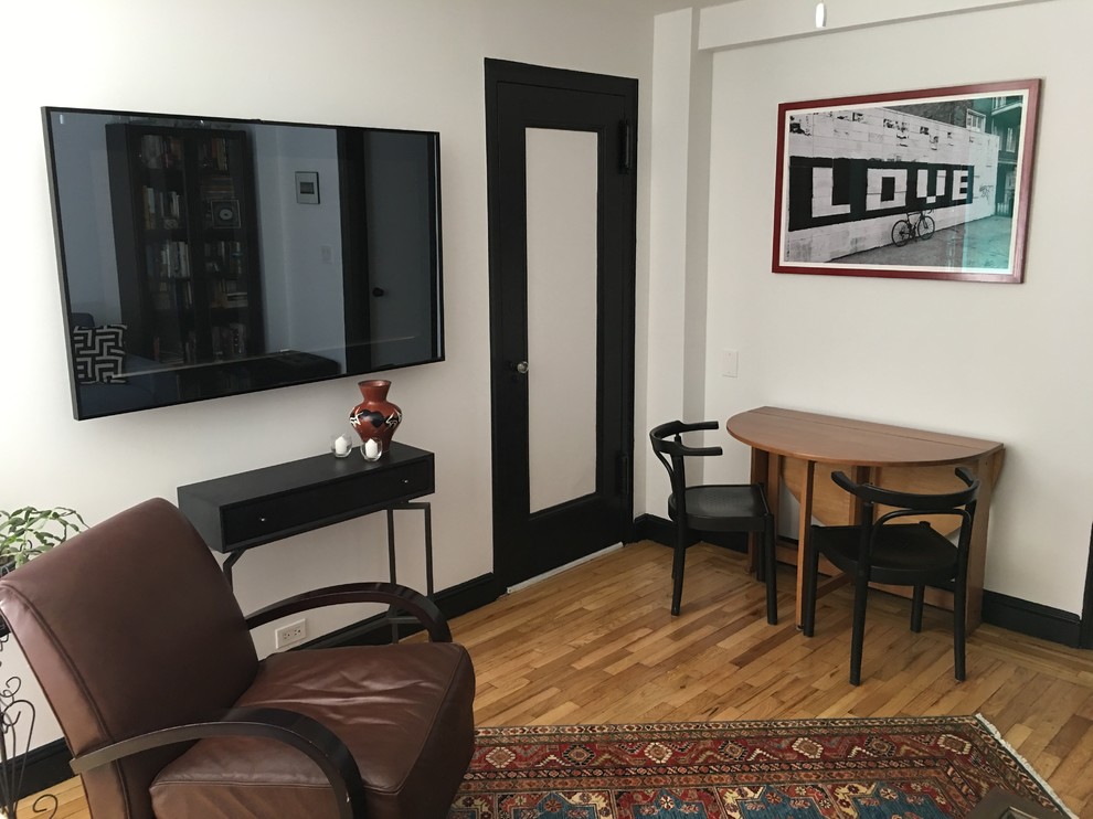 Foto di un piccolo soggiorno eclettico chiuso con pareti bianche, pavimento in legno massello medio, TV a parete e pavimento marrone