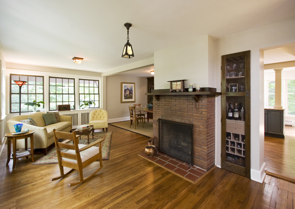 Idée de décoration pour un petit salon tradition ouvert avec une salle de réception, un mur gris, un sol en bois brun, une cheminée standard et un manteau de cheminée en brique.