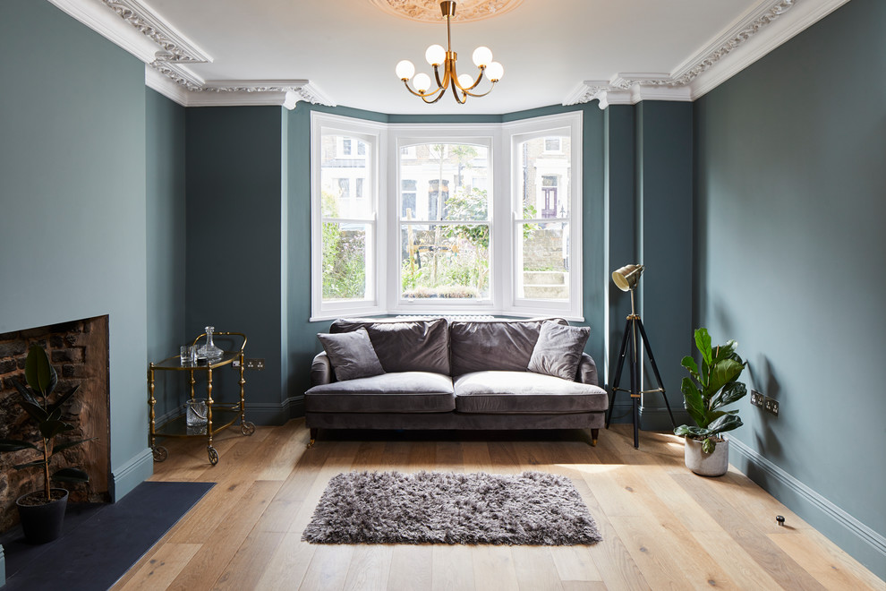 Klassisches Wohnzimmer mit grüner Wandfarbe, braunem Holzboden, Kamin und braunem Boden in London