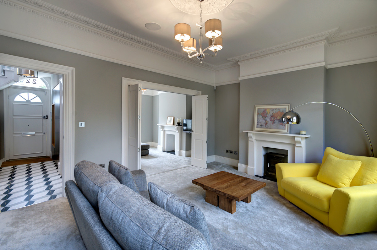 Aménagement d'un grand salon contemporain avec un mur gris, moquette, une cheminée standard, un téléviseur fixé au mur et un sol gris.