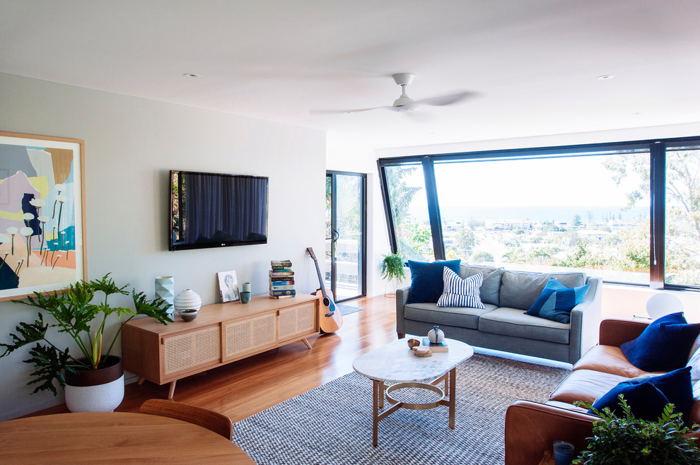 Foto di un soggiorno minimalista chiuso con pareti multicolore, pavimento in legno massello medio e TV a parete