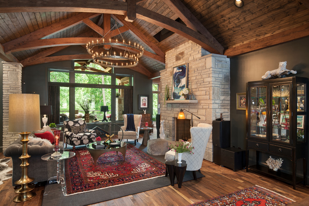 Rustic open plan living room in Other with black walls, medium hardwood flooring, a standard fireplace, a stone fireplace surround and brown floors.