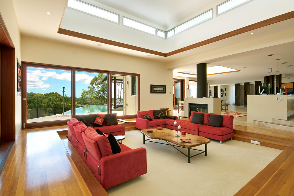 Modelo de salón abierto minimalista de tamaño medio con paredes beige, suelo de madera en tonos medios y todas las chimeneas