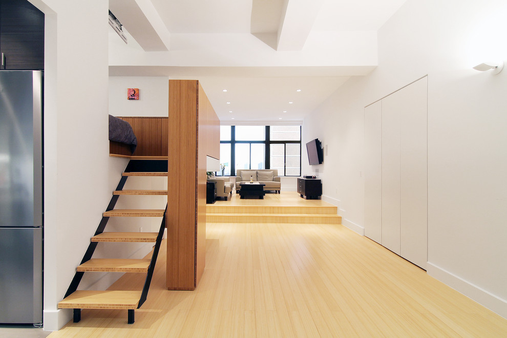 Diseño de salón tipo loft minimalista pequeño con paredes blancas, suelo de bambú y televisor colgado en la pared