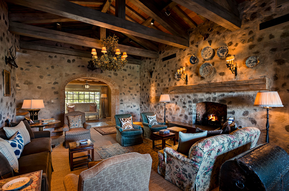 Fernseherloses Mediterranes Wohnzimmer mit beiger Wandfarbe, Kamin, Kaminumrandung aus Stein und Steinwänden in Phoenix