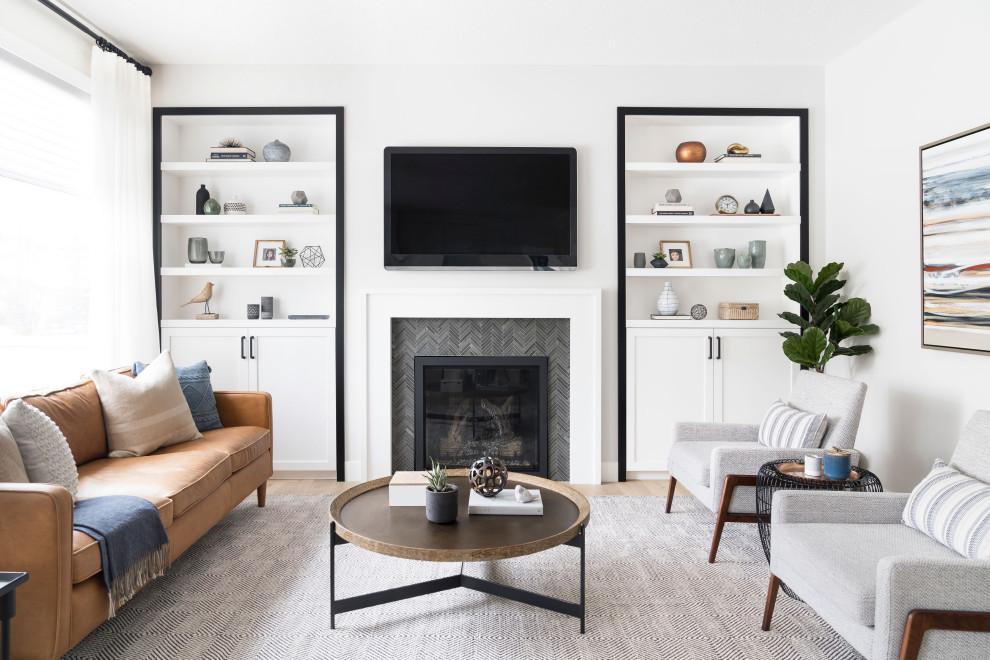 Mittelgroßes, Abgetrenntes Nordisches Wohnzimmer mit weißer Wandfarbe, Kamin, gefliester Kaminumrandung, TV-Wand, beigem Boden und braunem Holzboden in Calgary