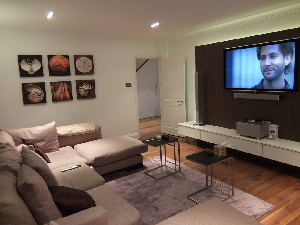 Foto di un soggiorno minimalista con parquet scuro e TV a parete