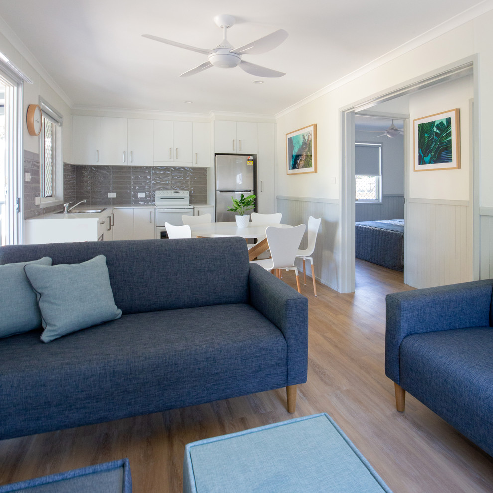 Kleines, Offenes Maritimes Wohnzimmer mit weißer Wandfarbe, Laminat, TV-Wand und braunem Boden in Gold Coast - Tweed