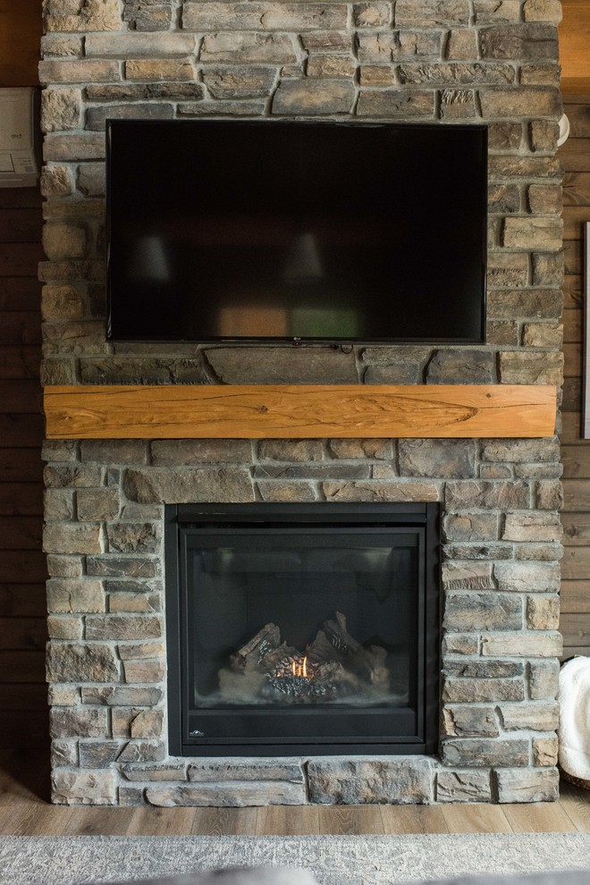 バンクーバーにある小さなラスティックスタイルのおしゃれなリビング (茶色い壁、リノリウムの床、標準型暖炉、レンガの暖炉まわり、壁掛け型テレビ、茶色い床) の写真