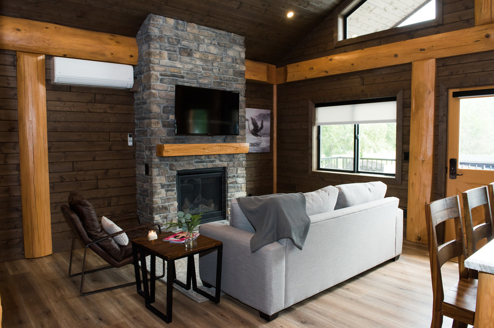 Photo of a rustic living room in Vancouver with brown walls, medium hardwood flooring, a standard fireplace, a stone fireplace surround, a wall mounted tv and brown floors.