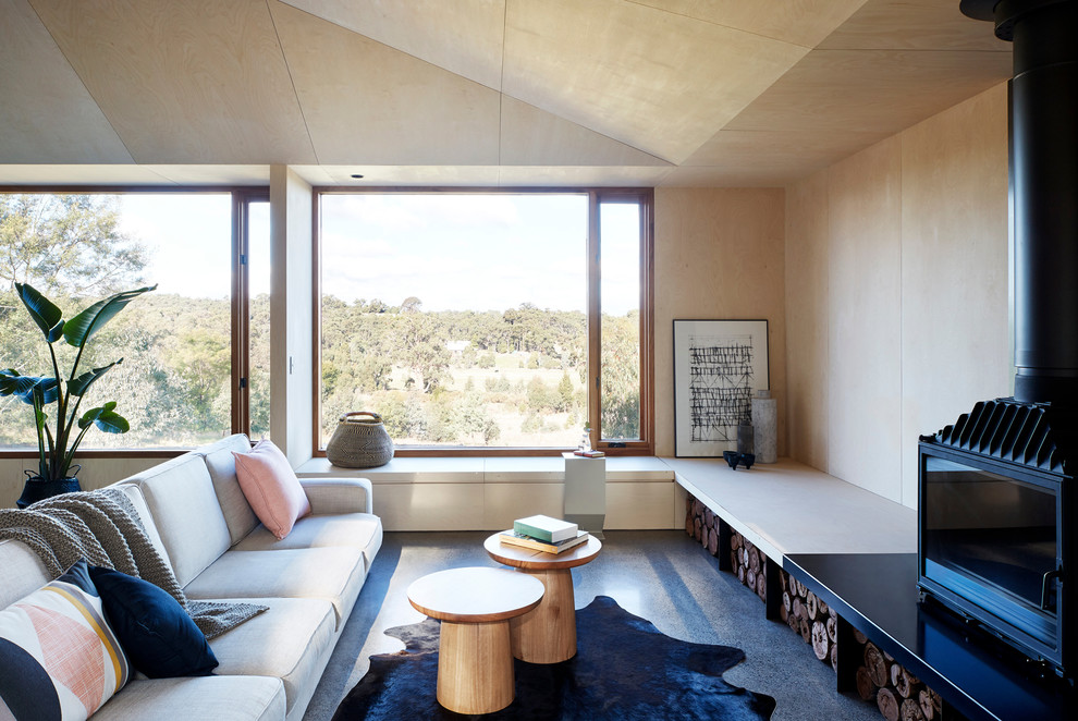 Ispirazione per un soggiorno minimal con pareti beige, pavimento in cemento, stufa a legna e pavimento grigio