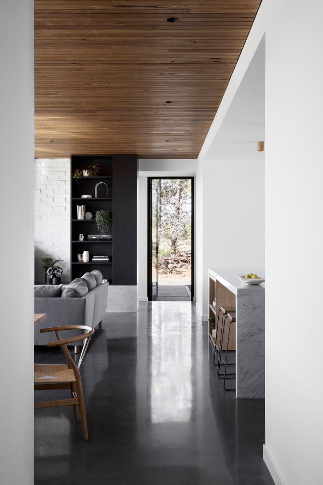 Großes, Offenes Modernes Wohnzimmer mit weißer Wandfarbe, Betonboden, Kaminofen, Kaminumrandung aus Backstein, TV-Wand und grauem Boden in Melbourne