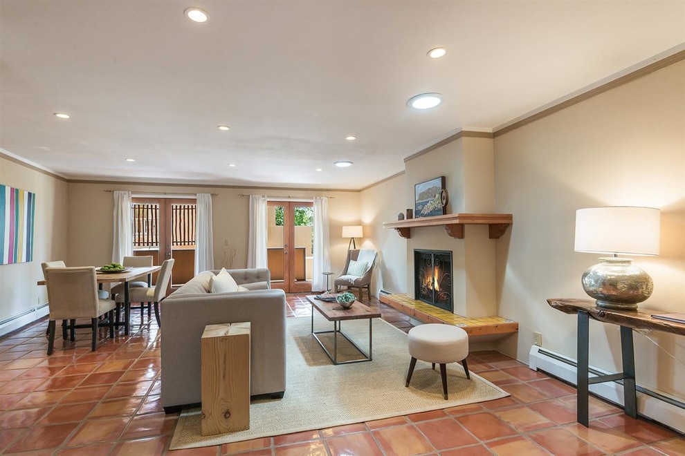 Exemple d'un salon sud-ouest américain de taille moyenne et ouvert avec un mur beige, tomettes au sol, une cheminée standard, un manteau de cheminée en carrelage, aucun téléviseur et un sol orange.