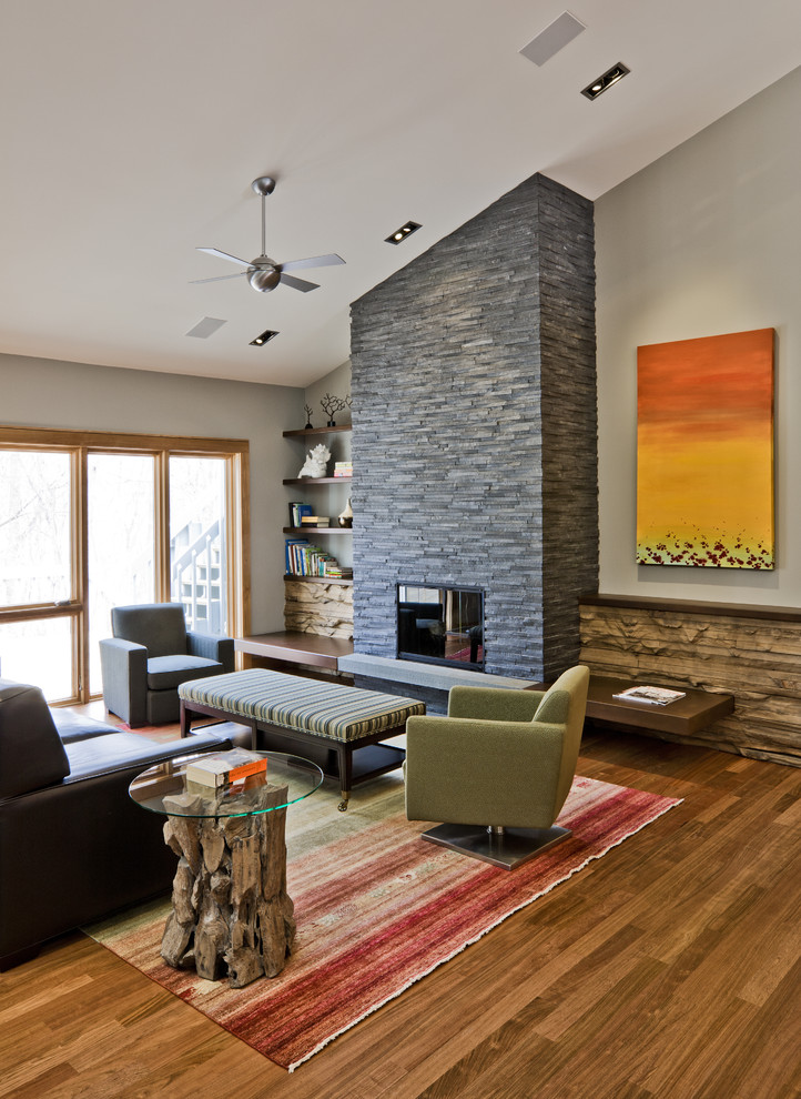 На фото: гостиная комната в стиле модернизм с фасадом камина из камня