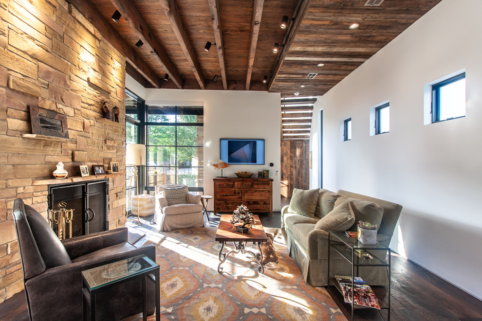 Rustikales Wohnzimmer mit weißer Wandfarbe, dunklem Holzboden, Kamin, Kaminumrandung aus Stein und braunem Boden in Dallas