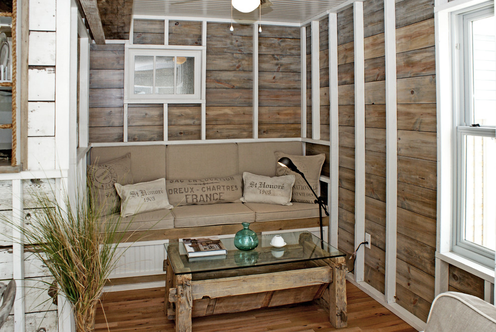 Imagen de salón costero con paredes marrones y suelo de madera en tonos medios