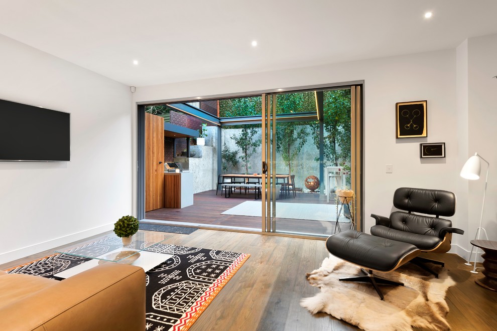 Ispirazione per un soggiorno minimal di medie dimensioni con sala formale, pareti bianche, pavimento in legno massello medio, TV a parete e pavimento marrone