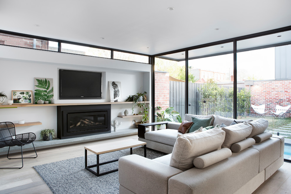 Offenes Modernes Wohnzimmer mit weißer Wandfarbe, hellem Holzboden, Gaskamin, TV-Wand und beigem Boden in Melbourne