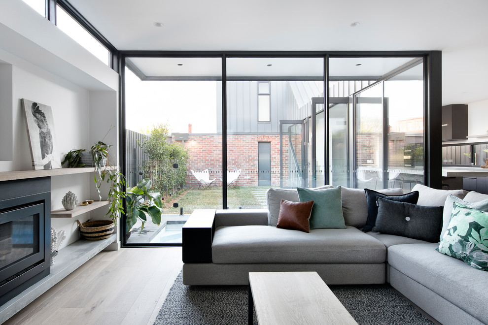 Modernes Wohnzimmer mit weißer Wandfarbe, hellem Holzboden, Kamin und Multimediawand in Melbourne