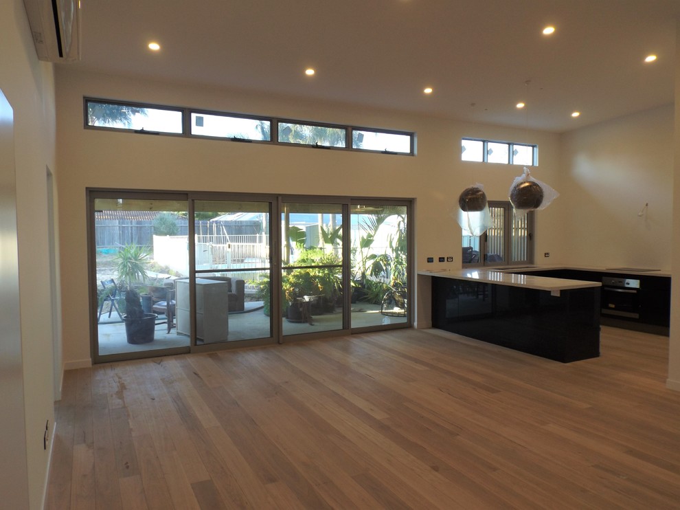 Large minimalist open concept medium tone wood floor living room photo in Central Coast with white walls