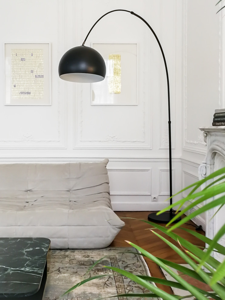パリにある高級な中くらいなコンテンポラリースタイルのおしゃれなリビング (白い壁、無垢フローリング、標準型暖炉、石材の暖炉まわり、茶色い床、テレビなし) の写真