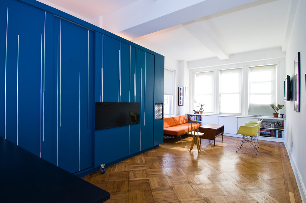 Small trendy enclosed medium tone wood floor living room photo in New York with white walls and a wall-mounted tv