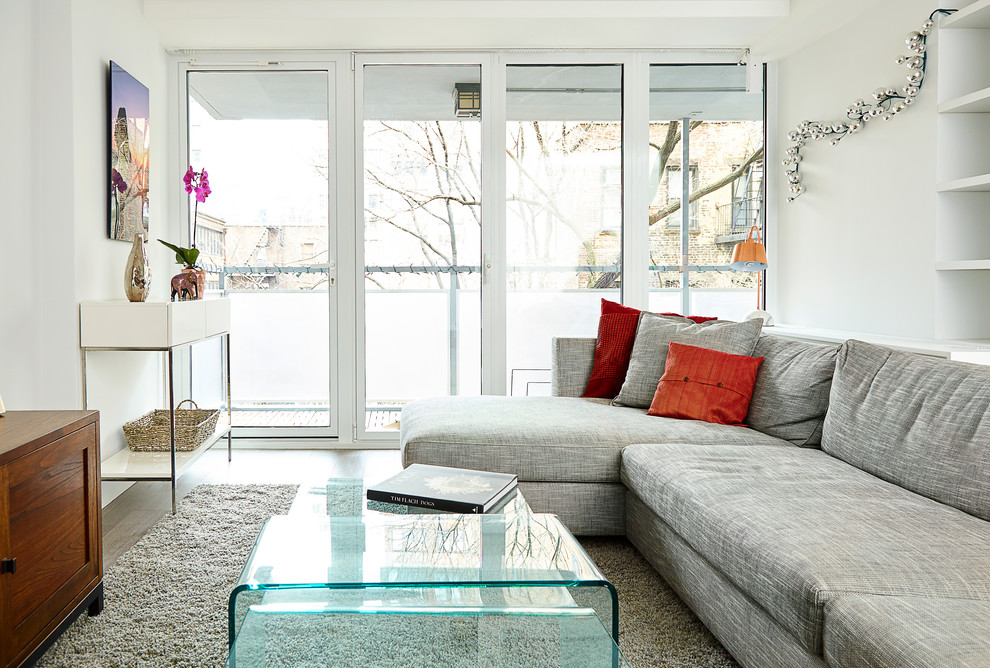 Esempio di un piccolo soggiorno minimal aperto con pareti bianche, parquet chiaro e TV a parete