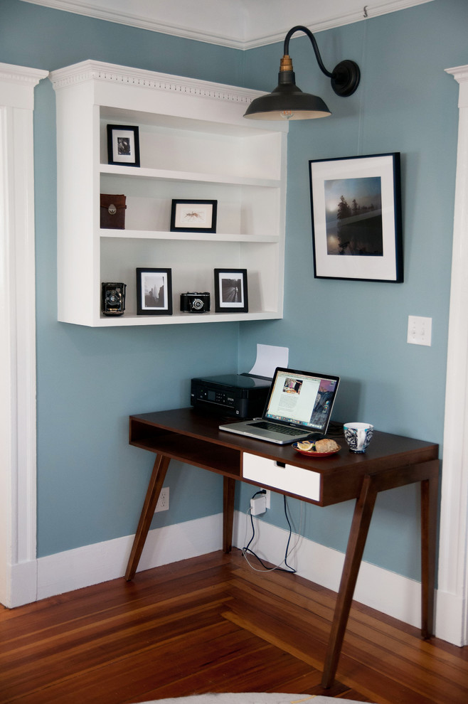 Idee per uno studio minimalista di medie dimensioni con pareti blu, pavimento in legno massello medio e nessun camino