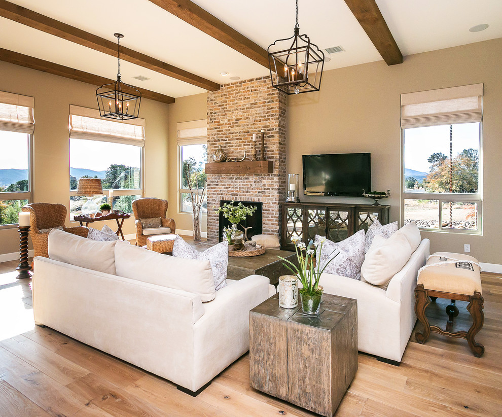 Example of a large southwest formal and open concept light wood floor living room design in Phoenix with beige walls, a standard fireplace, a brick fireplace and a wall-mounted tv