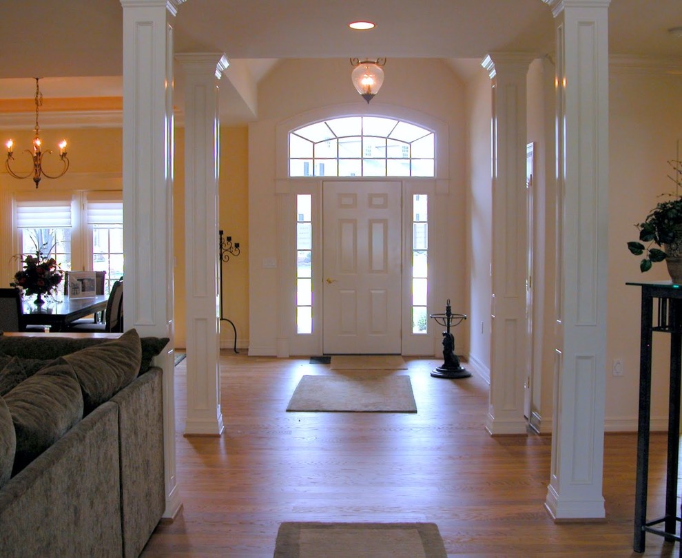 Exemple d'un grand salon chic ouvert avec une salle de réception, un mur blanc, un sol en bois brun, une cheminée standard, un manteau de cheminée en pierre et un téléviseur indépendant.