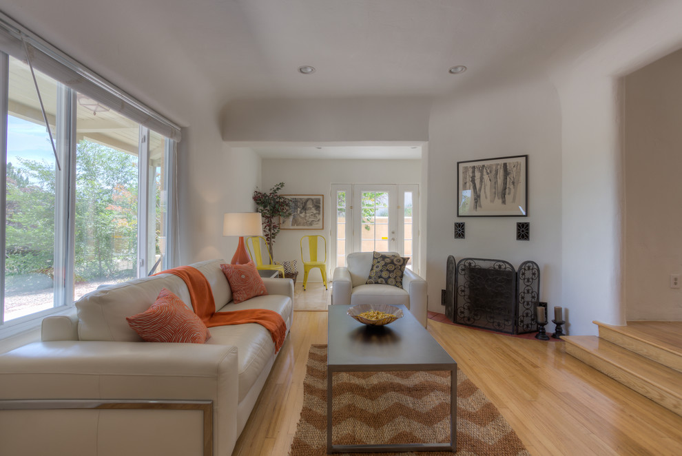 Mittelgroßes, Fernseherloses, Offenes Eklektisches Wohnzimmer mit weißer Wandfarbe, hellem Holzboden, Eckkamin und verputzter Kaminumrandung in Albuquerque