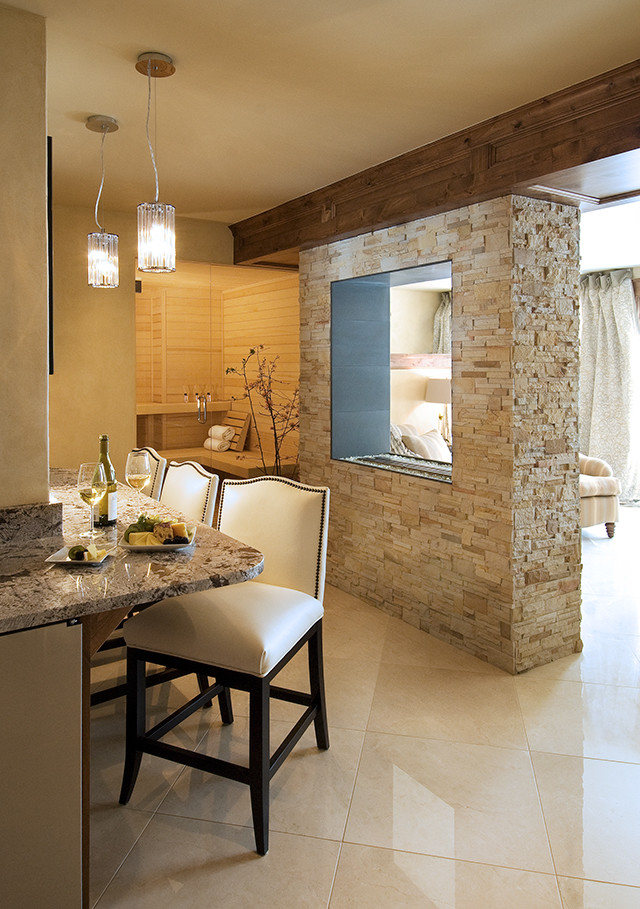 Ejemplo de salón con barra de bar abierto minimalista de tamaño medio con paredes beige, suelo de mármol, chimenea de doble cara, marco de chimenea de piedra y televisor colgado en la pared