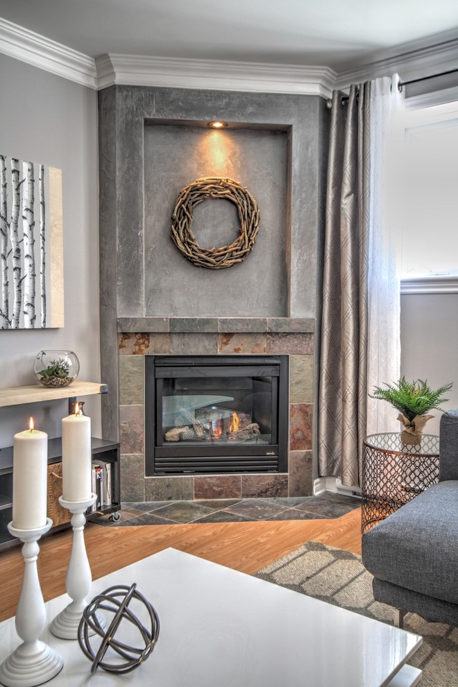 モントリオールにあるお手頃価格の中くらいなトランジショナルスタイルのおしゃれなリビング (グレーの壁、淡色無垢フローリング、コーナー設置型暖炉、コンクリートの暖炉まわり) の写真