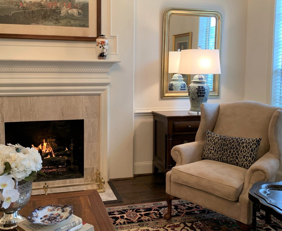 This is an example of a large traditional formal enclosed living room in Houston with white walls, medium hardwood flooring, a standard fireplace, a stone fireplace surround, no tv, brown floors and wainscoting.